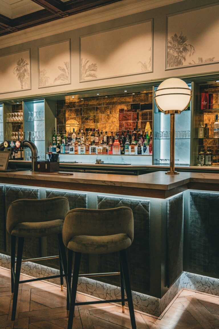 The hotel bar, with green velvet stools, a backlit back bar and a globe lamp, Oakley Hall Hotel