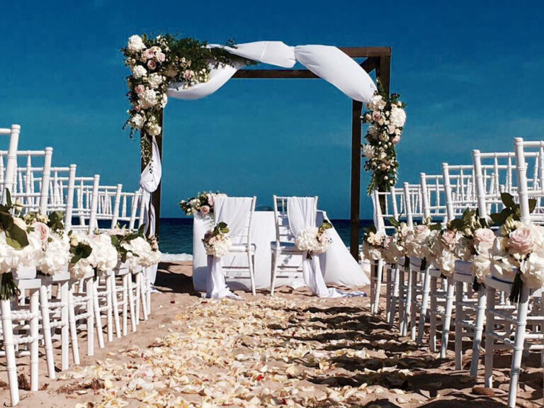 Wooden ceremony arch with roses and draped fabric, aisle of petals facing the sea, Oggi Sposi & Events