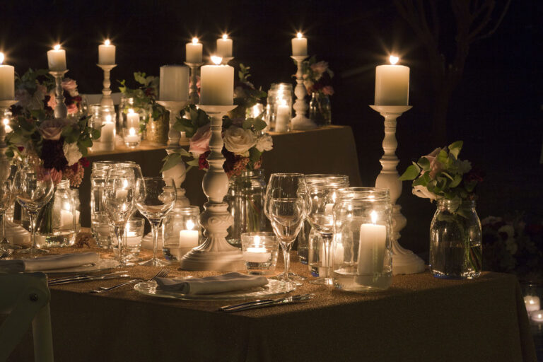 Candles of different heights, glassware and flowers on a table at night, Oggi Sposi & Events