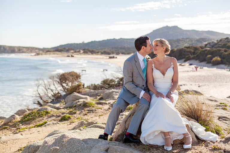 Couple on the rocks above a long white beach, Sardinia, Oggi Sposi & Events