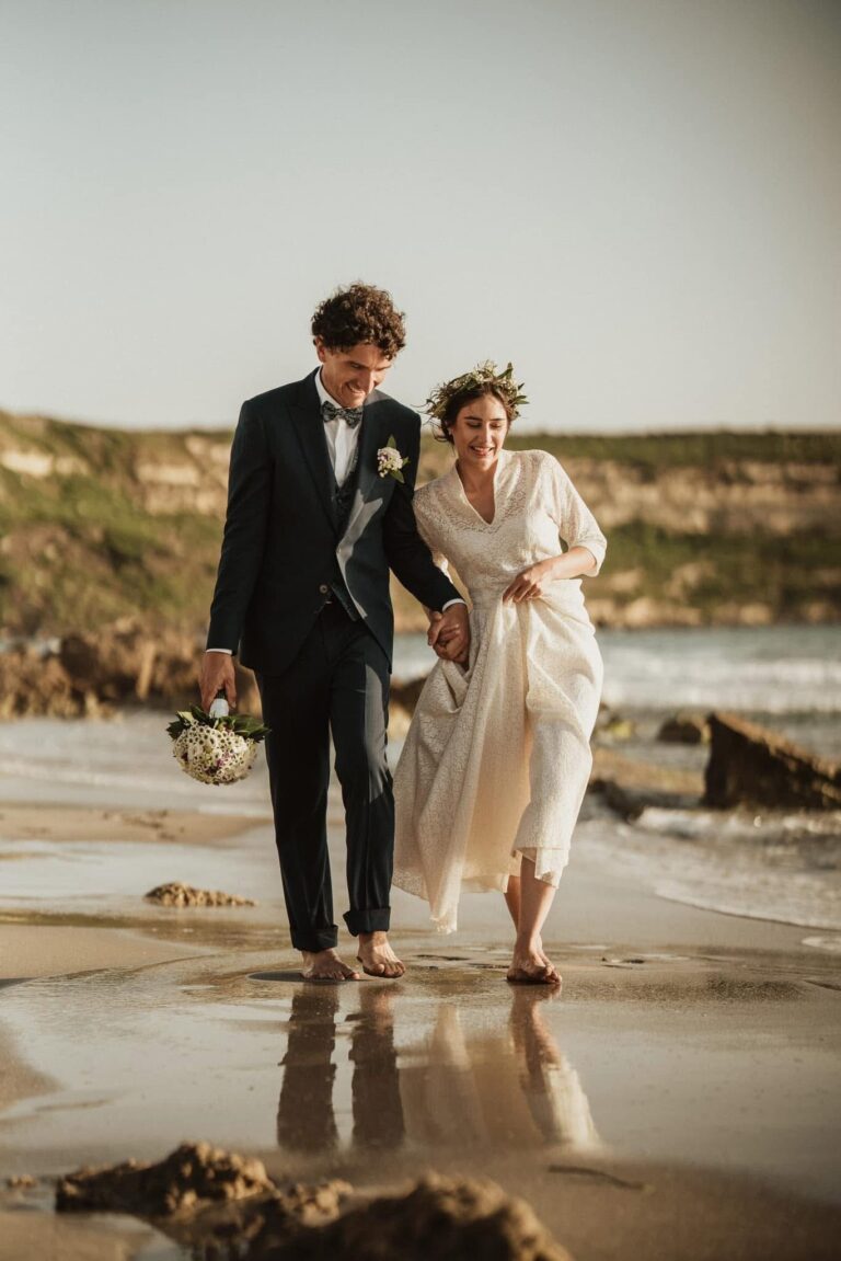 Couple walking barefoot along the shoreline, Oggi Sposi & Events