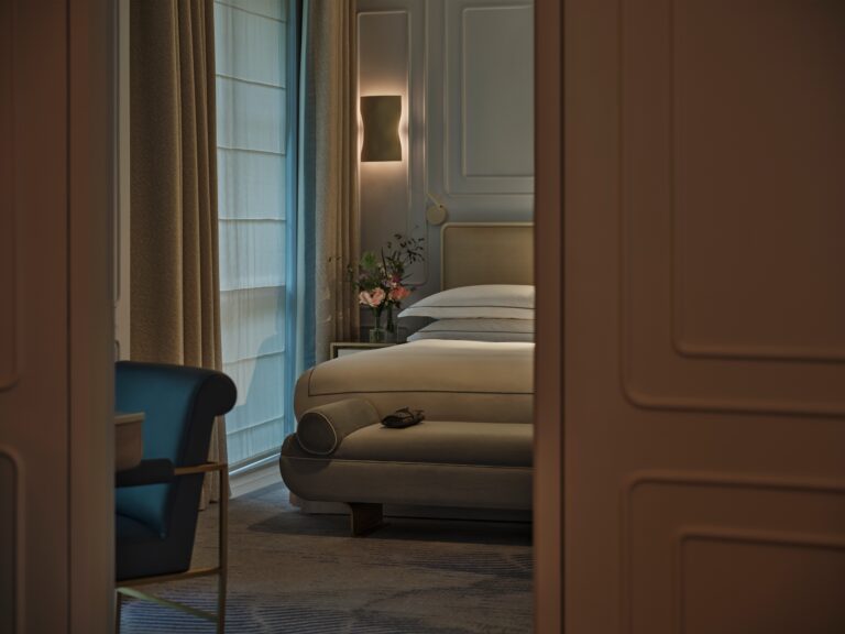 The bedroom of an Aldwych Corner Suite seen through the doorway from the living room, One Aldwych