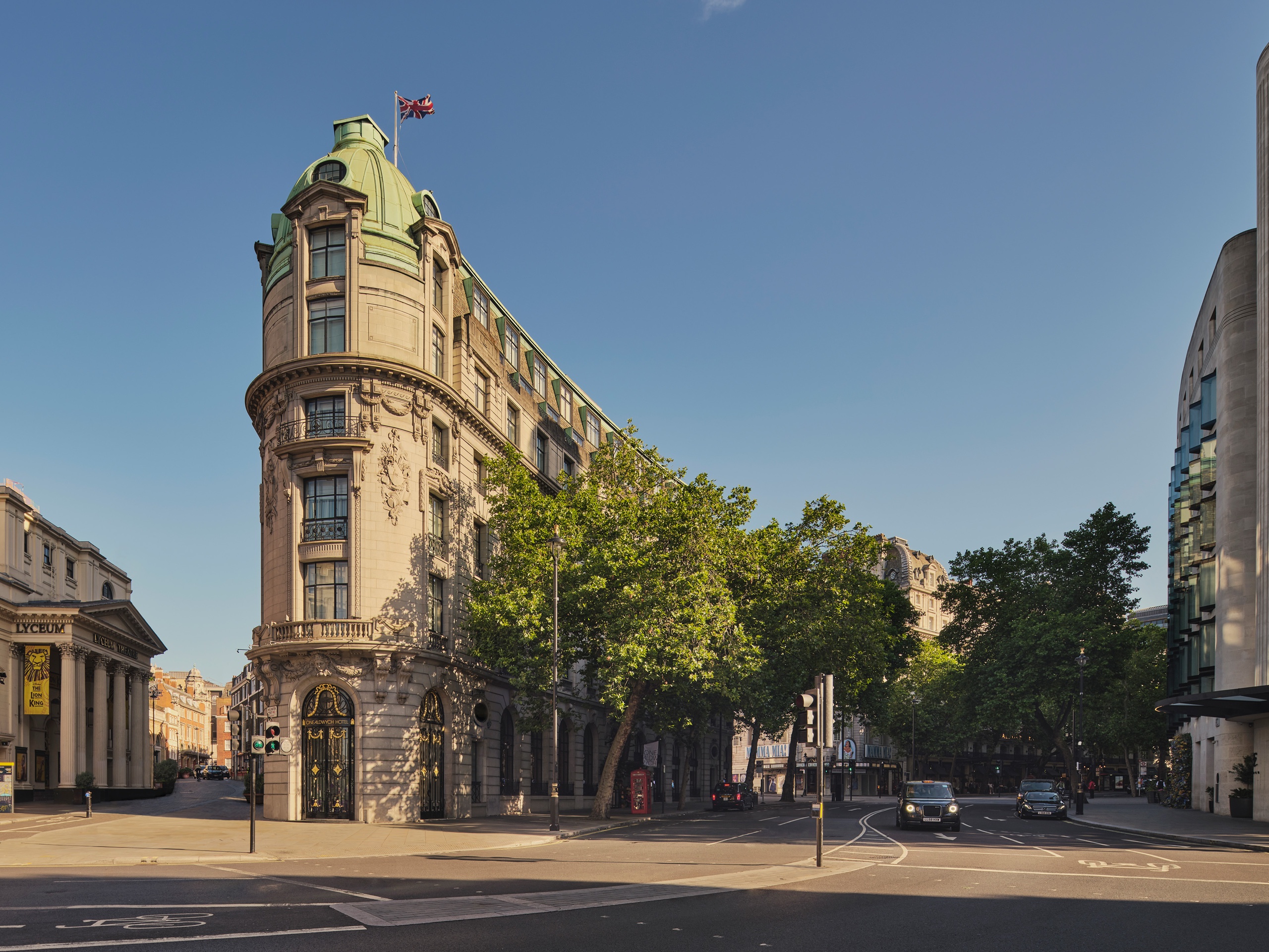 The Edwardian corner of One Aldwych, with its green copper cupola, where Aldwych meets the Strand on a clear morning, One Aldwych