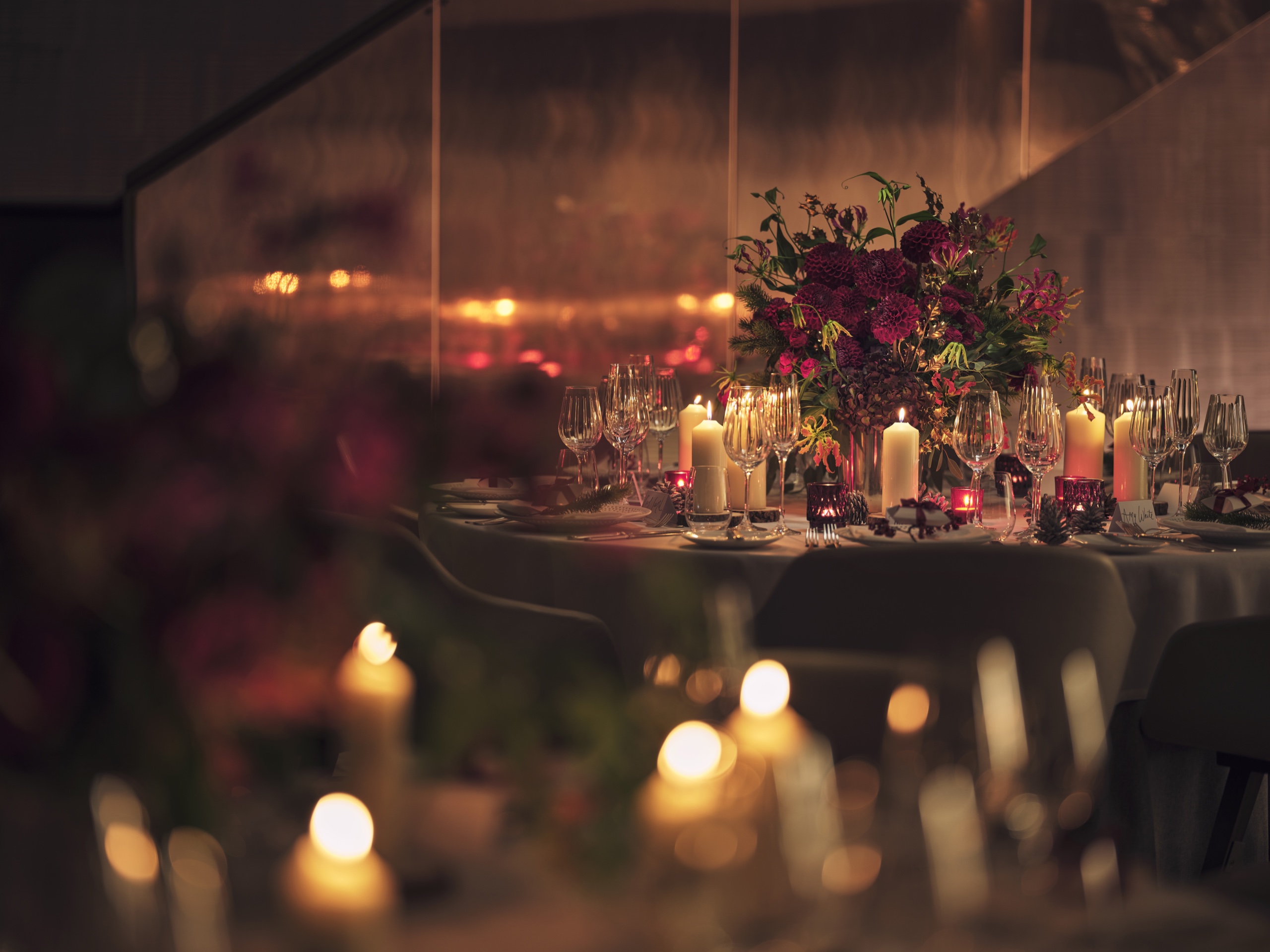 A round table dressed with pillar candles and a deep red floral arrangement in Downstairs at One Aldwych, One Aldwych