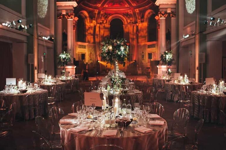 A warm amber-lit gala dinner, round tables and florals framed by the hall's soaring columns and painted apse, One Marylebone