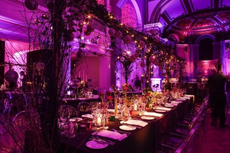 A dramatic purple-lit long banquet table dressed with hanging blossom branches under the galleries, One Marylebone
