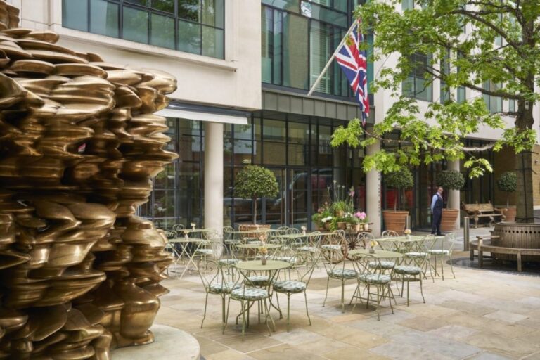 The private paved garden terrace with a bronze sculpture and cafe tables, One Marylebone