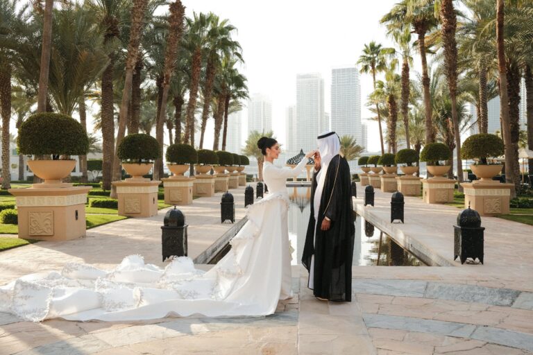 A couple on a palm-lined pathway with a long bridal train, One&Only Royal Mirage
