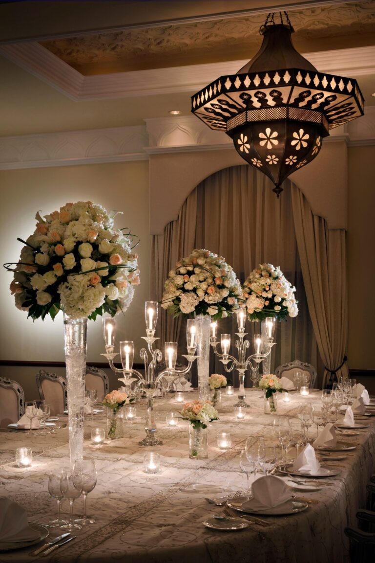 A banquet table with tall floral arrangements and candles under a pierced lantern, One&Only Royal Mirage