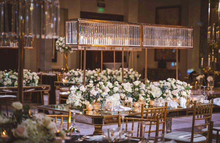 A long reception table with floral centrepieces and crystal light boxes, One&Only Royal Mirage