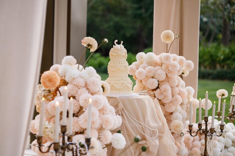 A wedding cake and flower arrangements on a table in the garden, One&Only Royal Mirage