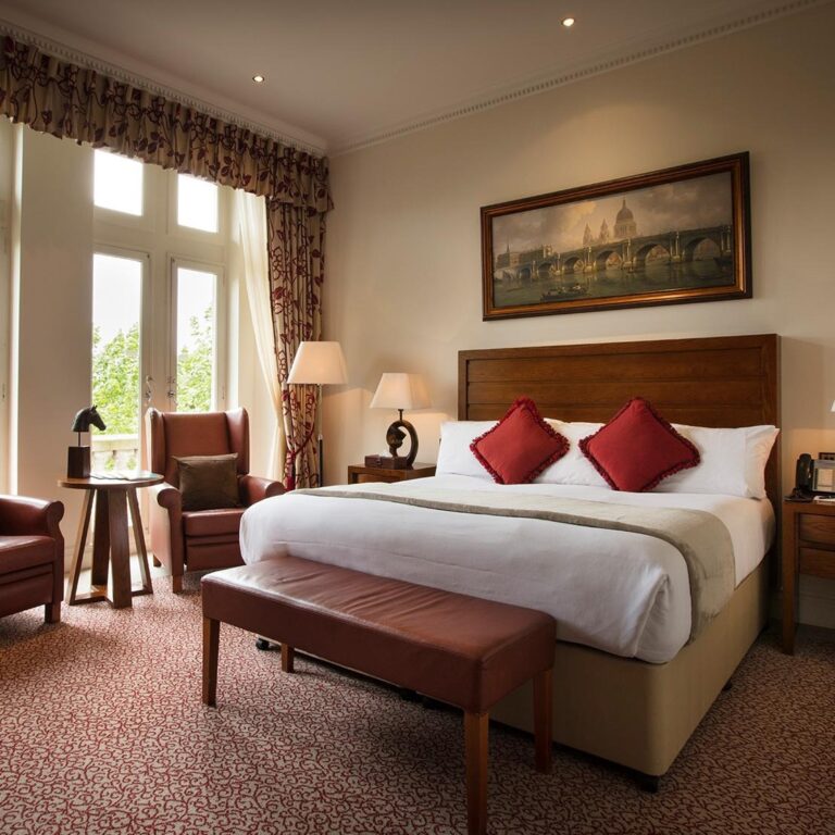 A garden view king bedroom with a bench at the foot of the bed, One Whitehall Place