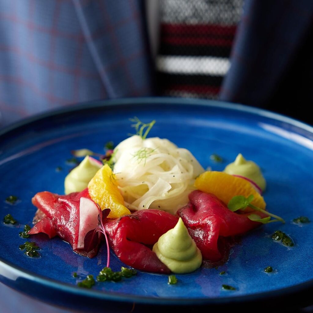 A plated starter of beetroot gravadlax on a blue plate, One Whitehall Place