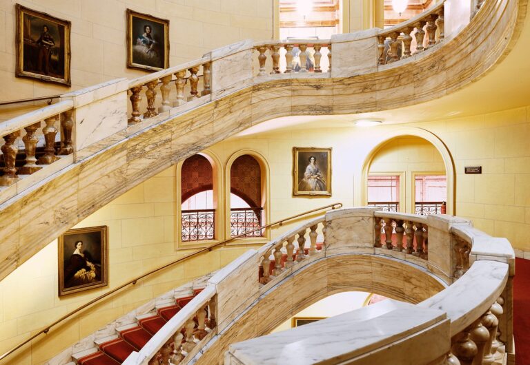 The curved marble staircase with portraits on the walls, One Whitehall Place