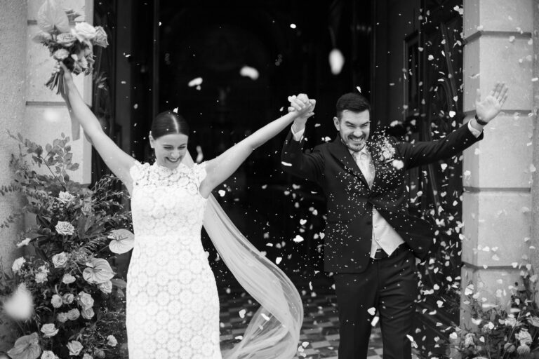 Arms in the air under a shower of petals as the couple leave the ceremony, Villa Semenza, black and white, Ordine della Giarrettiera