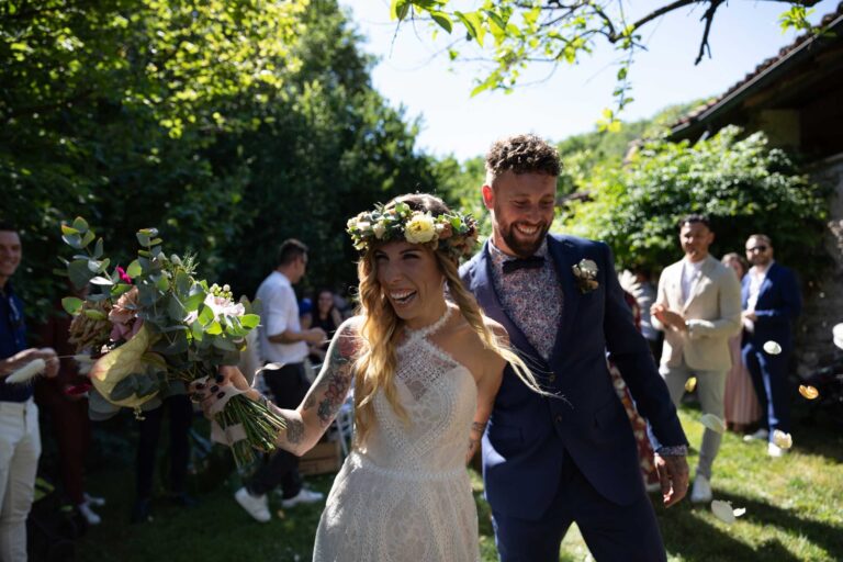 Bride and groom in flower crowns laughing with guests in the garden, Mulino dell'Olio, Ordine della Giarrettiera