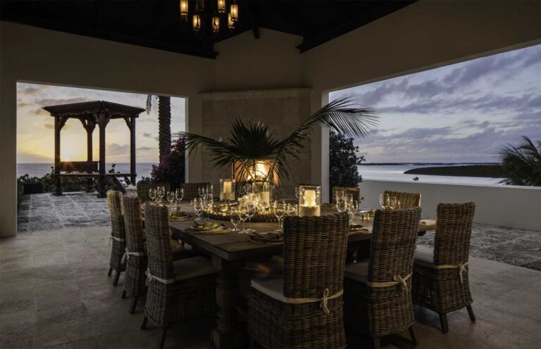 Long dining table set under a pavilion at dusk, facing the water, Over Yonder Cay