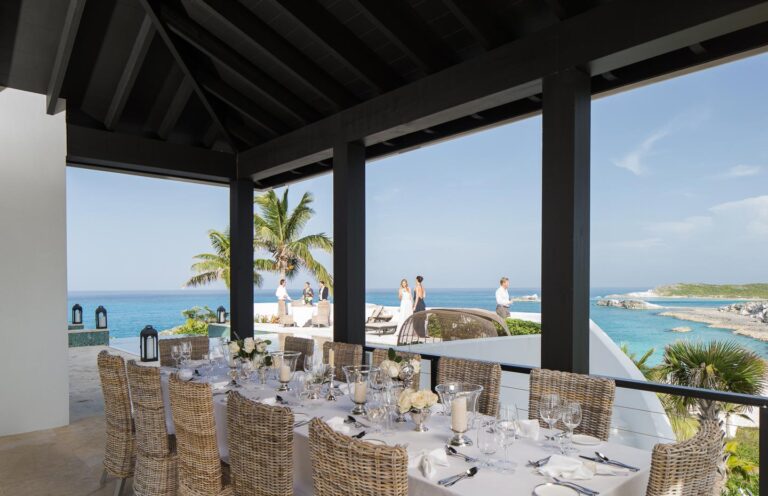 Long dining table on a covered terrace overlooking the water, Over Yonder Cay