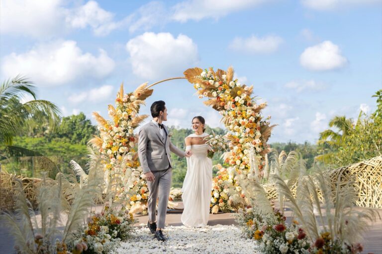 A couple beneath a floral arch at the Bamboo Nest, Padma Resort Ubud