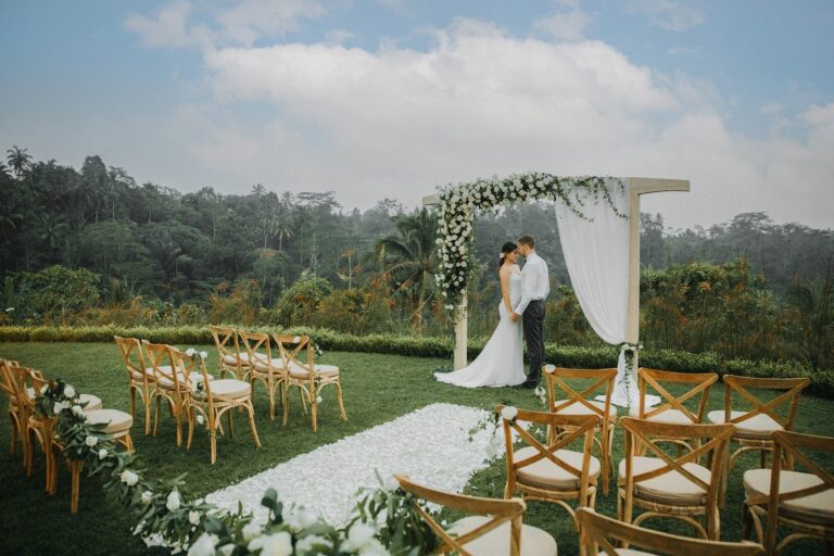 A couple at a floral ceremony arch on the lawn, Padma Resort Ubud