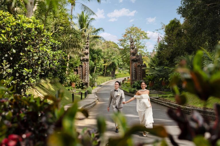 A couple walking past a Balinese gateway in the resort grounds, Padma Resort Ubud