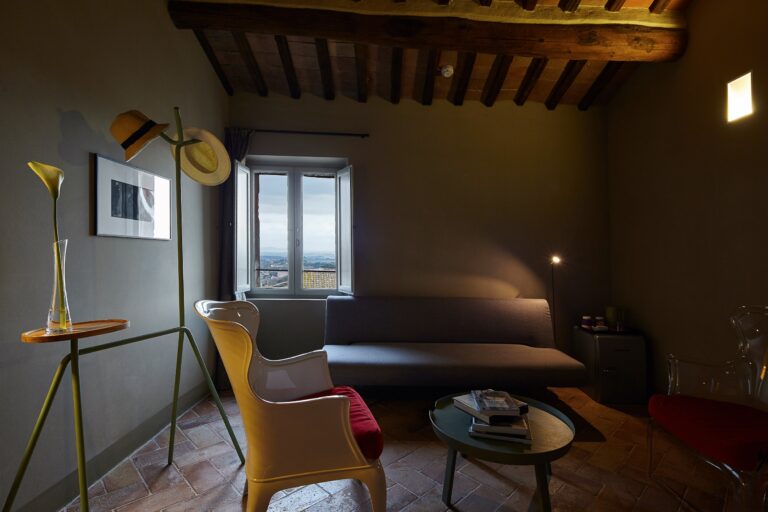 A design lounge under a beamed ceiling with a Siena-view window, Palazzetto Rosso
