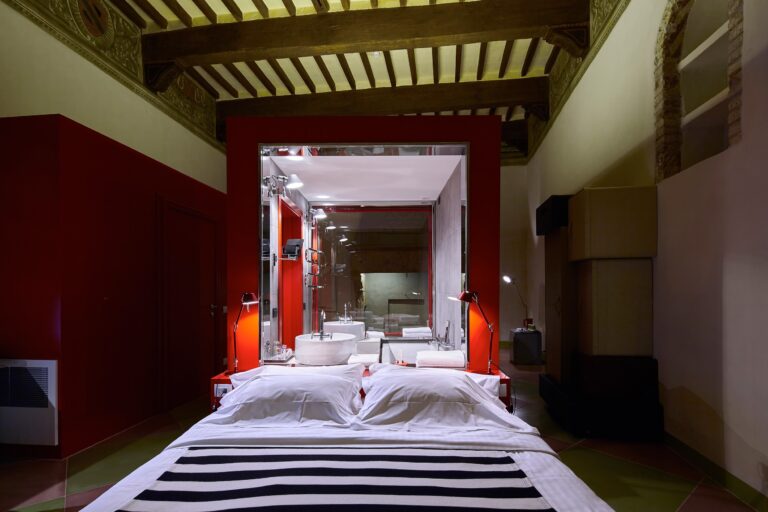 A red-lacquer design suite beneath a frescoed beamed ceiling, Palazzetto Rosso