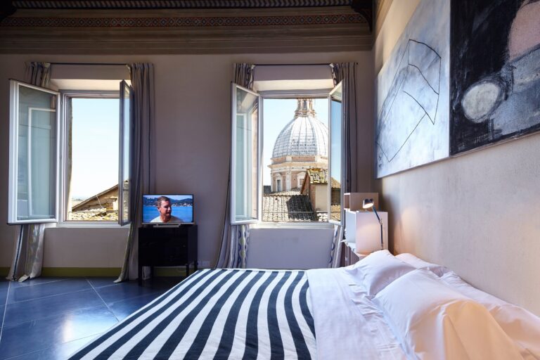 A design bedroom framing the Duomo cupola through twin windows, Palazzetto Rosso
