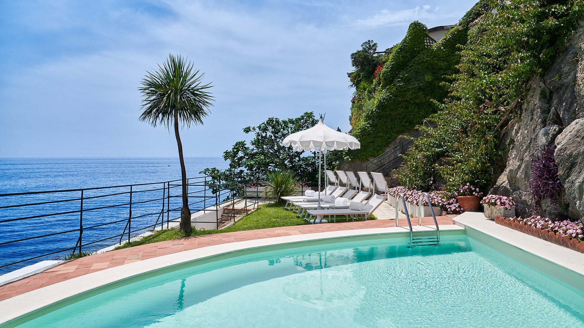 Pool terrace above the sea, framed by palms, Palazzo Avino
