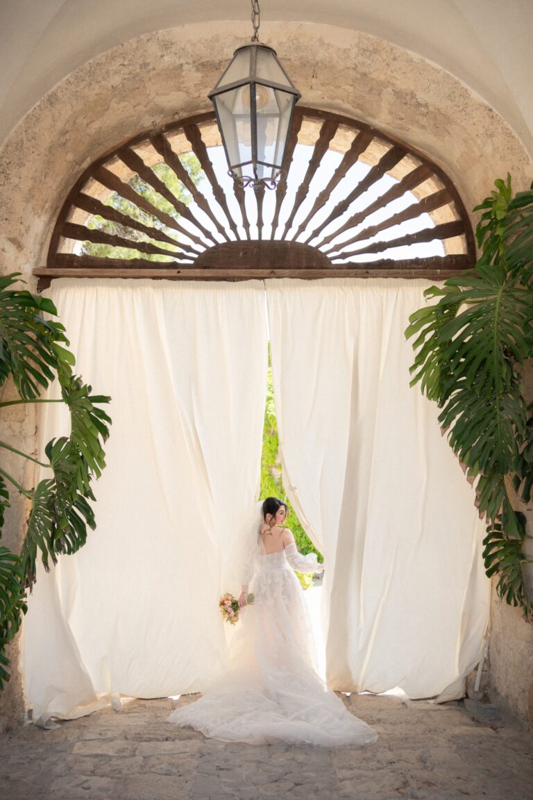 White curtains drawn across a fanlight arch, the bride waiting behind them, Pangiunìa Wedding