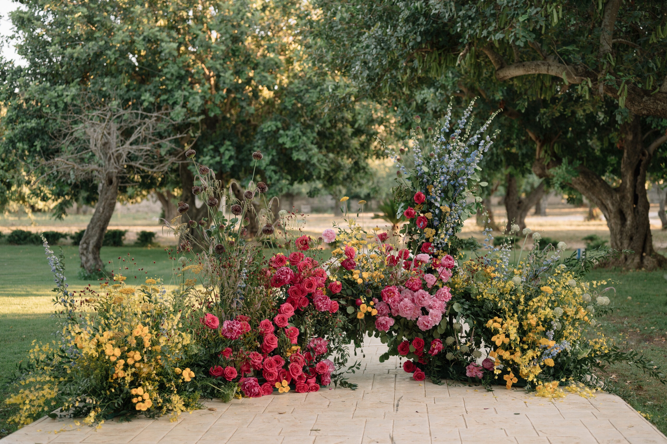 A flower wall built at knee height under old citrus trees: roses, cosmos, delphinium, Pangiunìa Wedding
