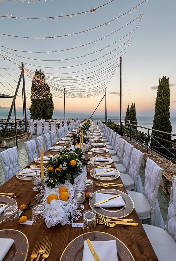 A terrace banquet table with lemons and sea views at sunset