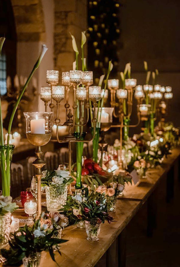 A candlelit banquet table with candelabra and green stems