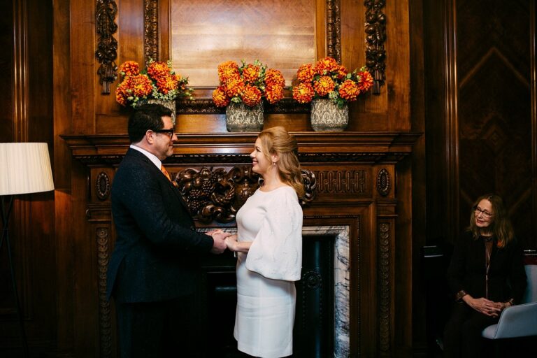 Vows by the carved fireplace in a panelled room at Old Marylebone Town Hall, London, Paola De Paola Photography