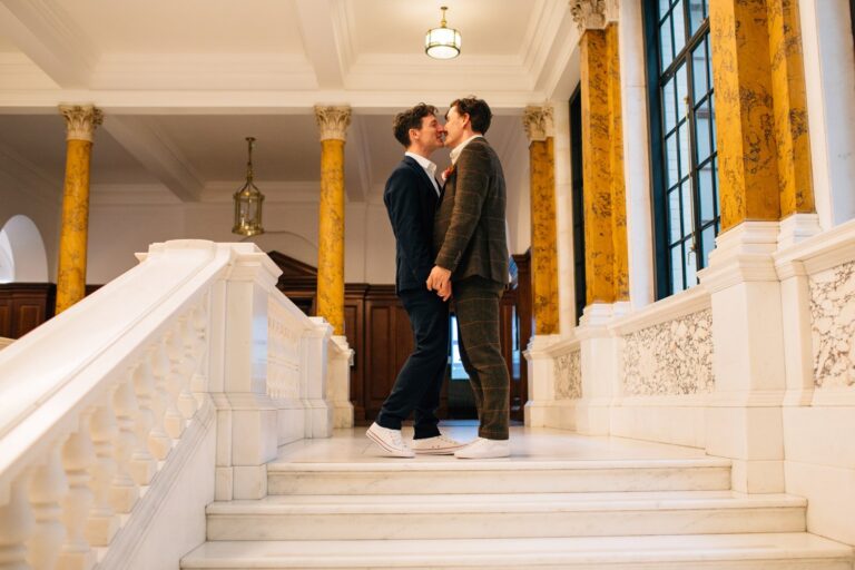 Two grooms on the marble staircase of Camden Town Hall, London, Paola De Paola Photography