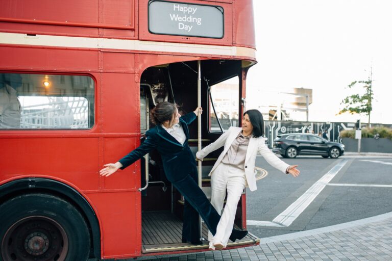 Two brides step off a red Routemaster on the way to Old Marylebone Town Hall, Paola De Paola Photography