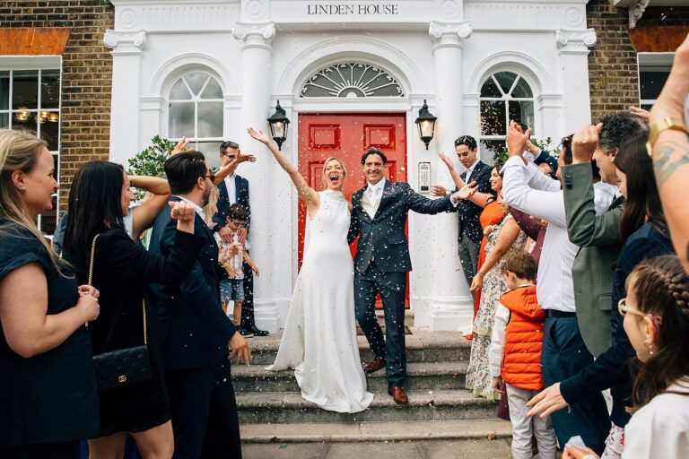 Guests cheer the couple on the steps of Linden House Riverside, London, Paola De Paola Photography