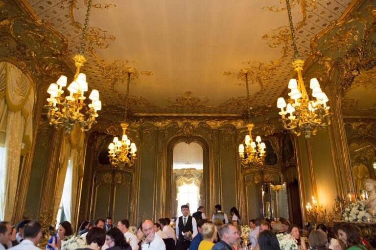 The wedding breakfast beneath the chandeliers of the gilded dining room at Cliveden House, Paola De Paola Photography