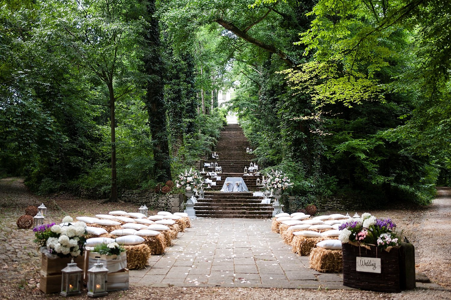 Hay-bale seating and rose petals set for a forest ceremony at Frassanelle, Veneto, Paola De Paola Photography
