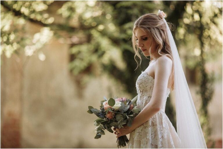 Bride in a veil holding a pastel bouquet, with a softly styled updo, Paola Giancola Makeup