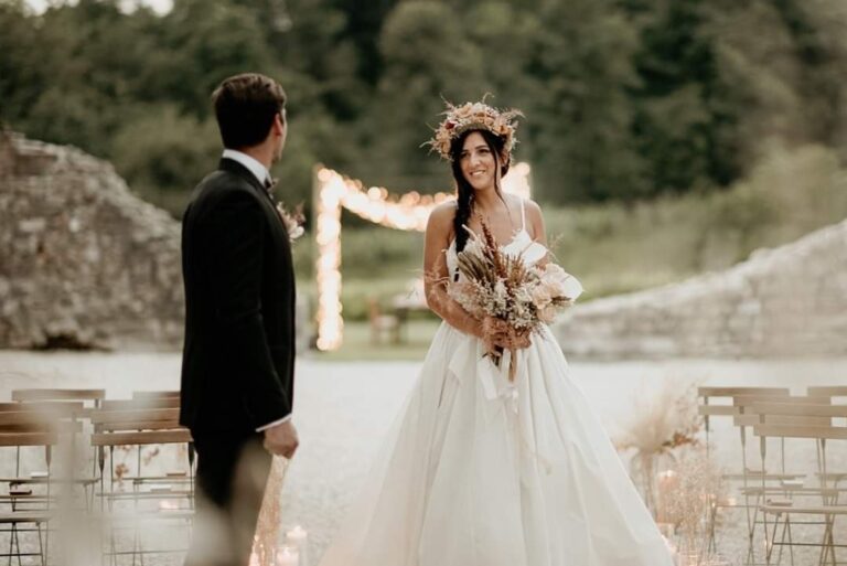 Bride in a floral crown and groom in front of a ceremony set-up in a ruined courtyard, Paola Giancola Makeup