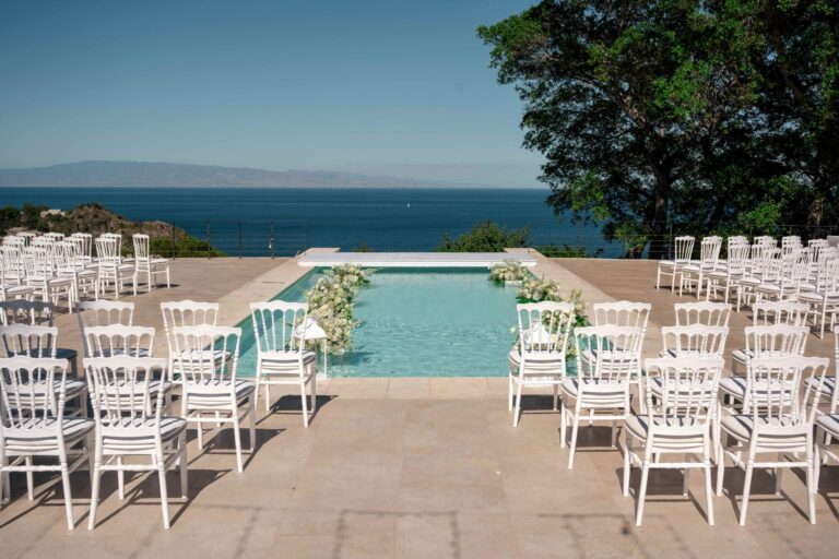 White chairs set either side of the pool before the ceremony, the sea beyond, Villa Mon Repos, Taormina, Paola Lapi Luxury Event