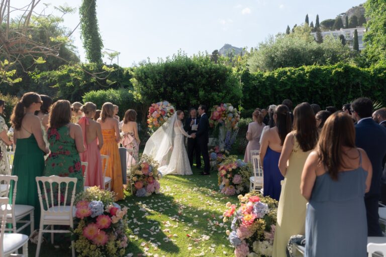 Guests standing on the lawn during a symbolic ceremony among pastel flowers, Villa Mon Repos, Taormina, Paola Lapi Luxury Event