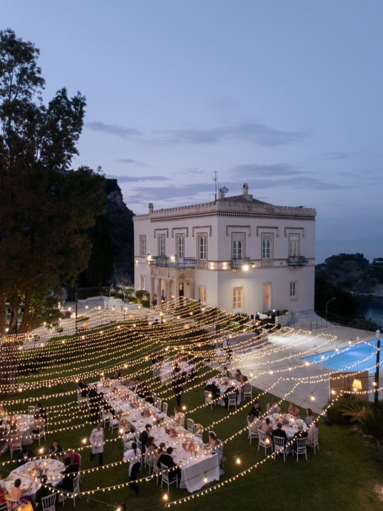 The villa garden lit for dinner after dark, tables under lights, Villa Mon Repos, Taormina, Paola Lapi Luxury Event