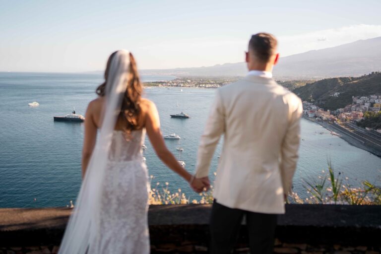 The couple seen from behind on a terrace above the bay, yachts at anchor below, Taormina, Paola Lapi Luxury Event