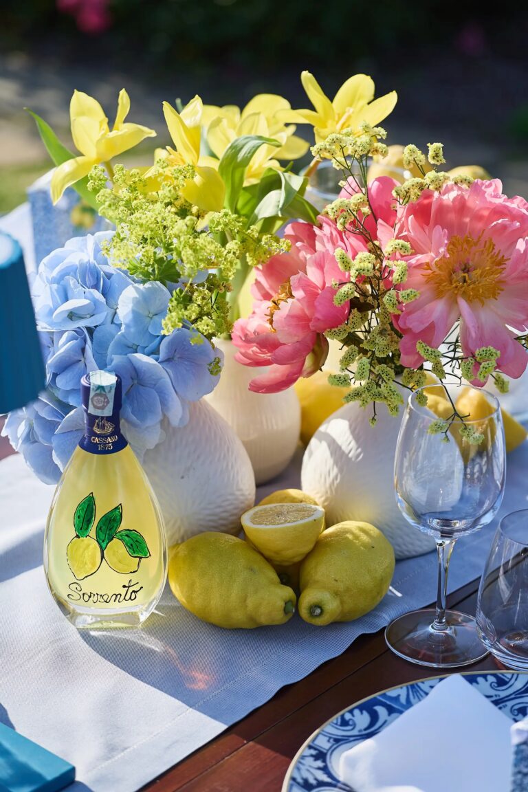 The same bottle on the table, tulips and peonies behind, whole lemons at the base, Paolo Cicognani Weddings & Events
