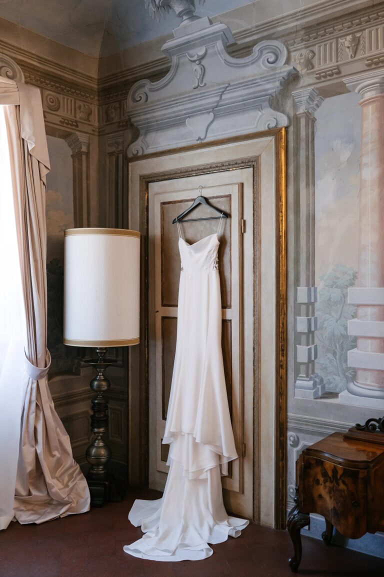The dress on the door of a frescoed room, the train out across the floor, Paolo Cicognani Weddings & Events