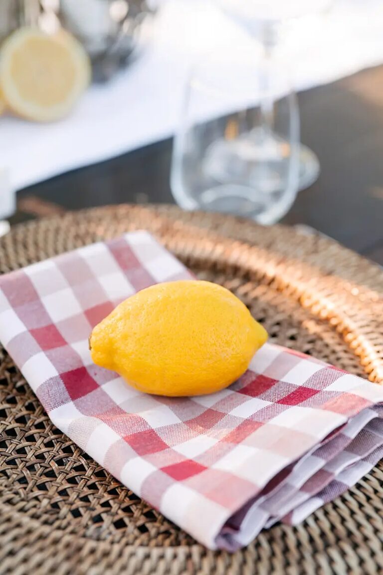 One lemon on a red gingham napkin, on a rattan charger, Paolo Cicognani Weddings & Events
