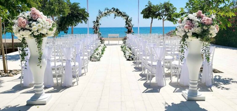 Aisle between white vases and a floral arch facing the sea, Coral Residences, Paphos Weddings Made Easy