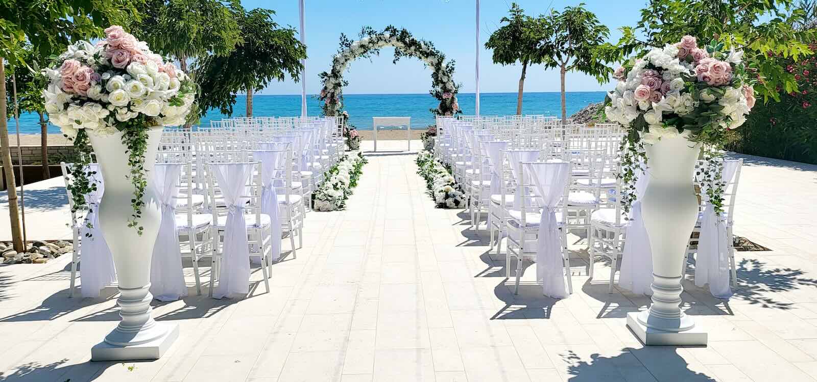 Aisle between white vases and a floral arch facing the sea, Coral Residences, Paphos Weddings Made Easy